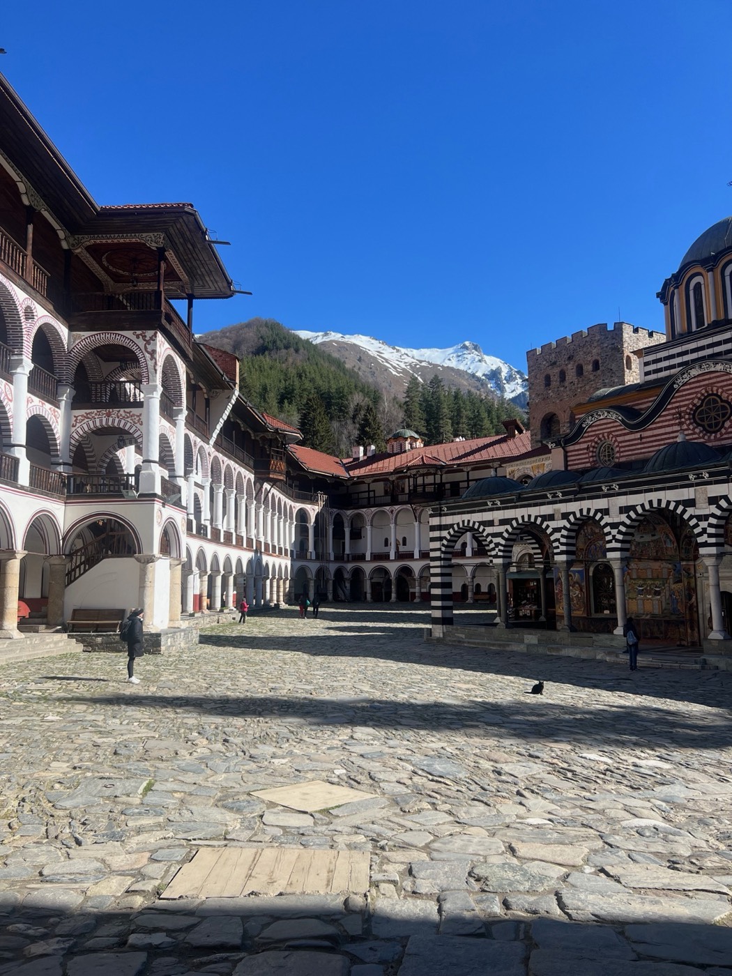 Rila Monastery courtyard with striped arcades and snowy mountains