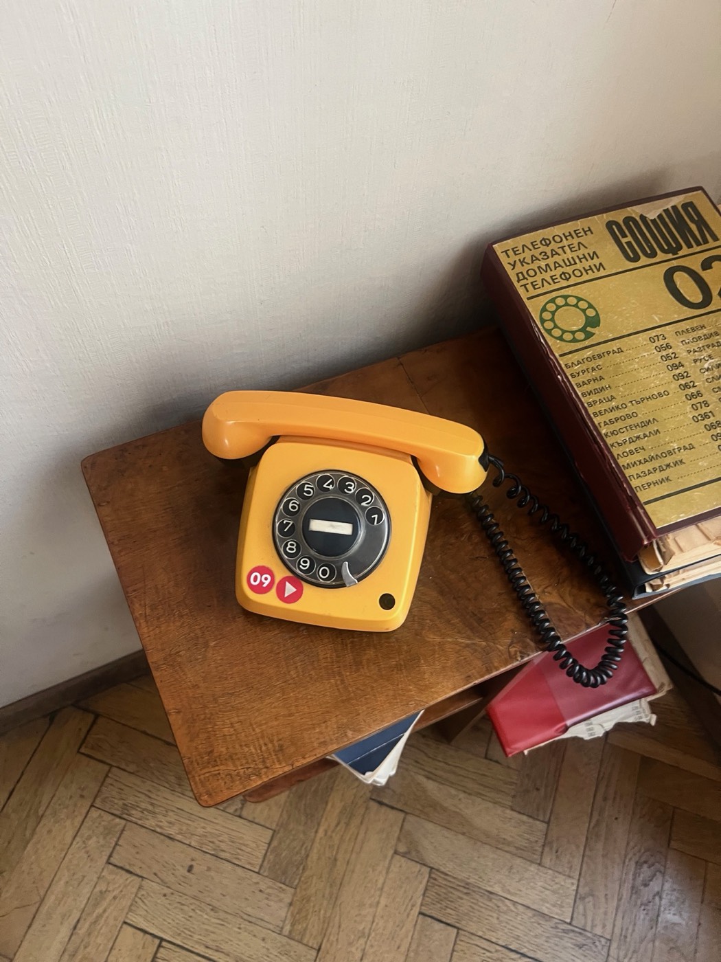 A yellow rotary telephone on a wooden side table